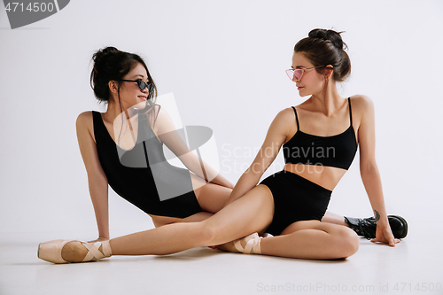 Image of Two young female ballet dancers against white studio background