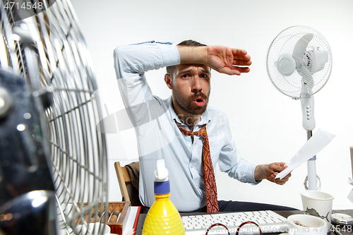 Image of Young man ssuffering from the heat in the office