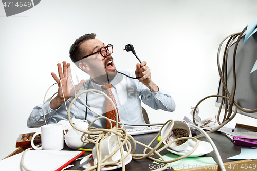 Image of Young man tangled in wires on the workplace