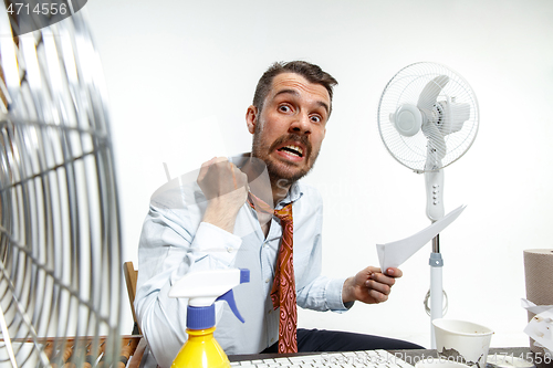 Image of Young man ssuffering from the heat in the office