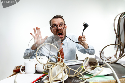 Image of Young man tangled in wires on the workplace