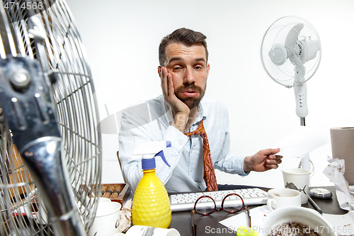 Image of Young man ssuffering from the heat in the office