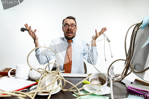 Image of Young man tangled in wires on the workplace