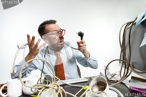 Image of Young man tangled in wires on the workplace