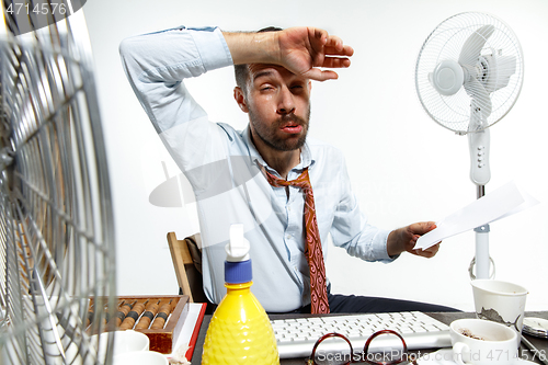 Image of Young man ssuffering from the heat in the office