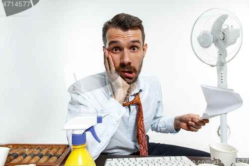 Image of Young man ssuffering from the heat in the office