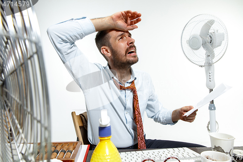 Image of Young man ssuffering from the heat in the office