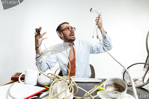 Image of Young man tangled in wires on the workplace