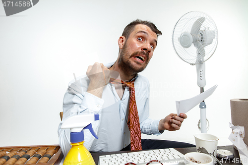 Image of Young man ssuffering from the heat in the office