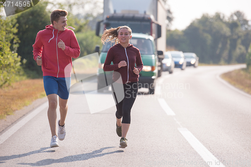 Image of young couple jogging along a country road