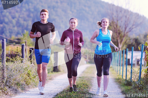 Image of young people jogging on country road