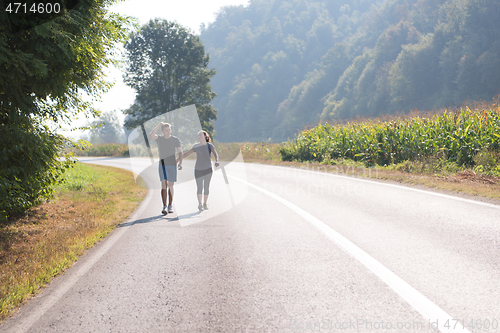 Image of young couple jogging along a country road