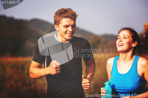 Image of young couple jogging along a country road