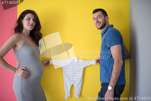 Image of young couple holding baby bodysuits