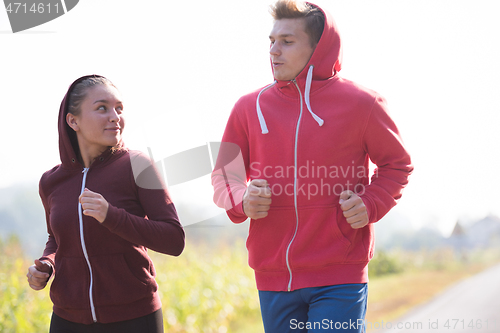 Image of young couple jogging along a country road