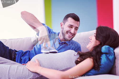 Image of young pregnant couple relaxing on sofa