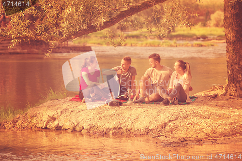Image of friends smoking hookah on the river bank