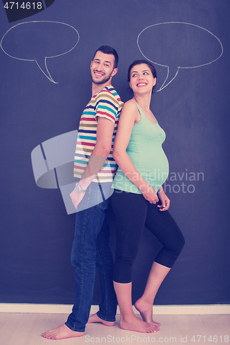 Image of pregnant couple writing on a black chalkboard