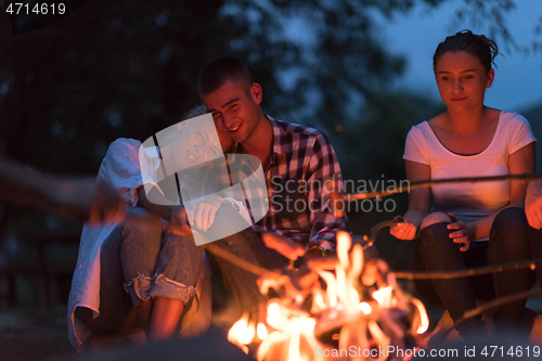 Image of young friends relaxing around campfire