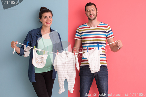 Image of young couple holding baby bodysuits