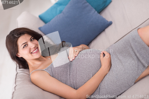 Image of pregnant woman sitting on sofa at home