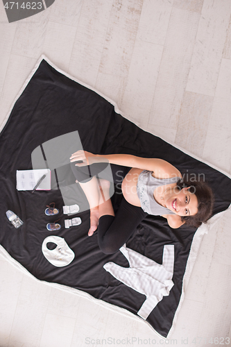 Image of top view of pregnant woman checking list of baby clothes