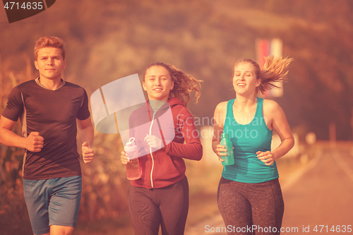 Image of young people jogging on country road