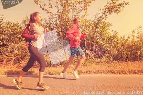 Image of young couple jogging along a country road