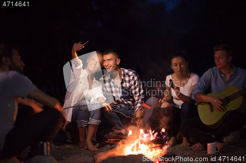 Image of young friends relaxing around campfire