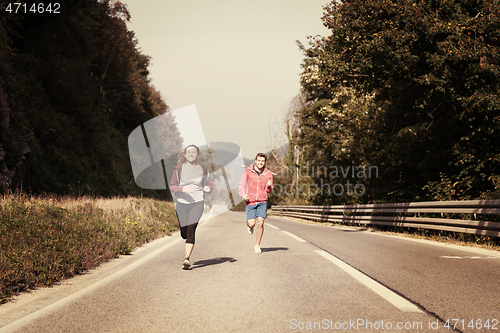 Image of young couple jogging along a country road