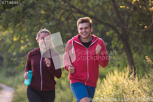 Image of young couple jogging along a country road