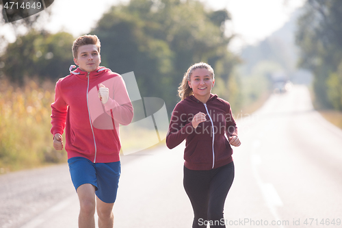 Image of young couple jogging along a country road