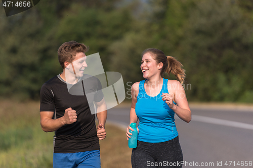 Image of young couple jogging along a country road