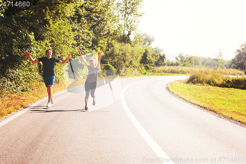 Image of young couple jogging along a country road