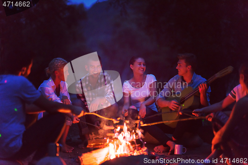 Image of young friends relaxing around campfire