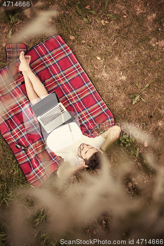 Image of top view of man using a laptop computer under the tree