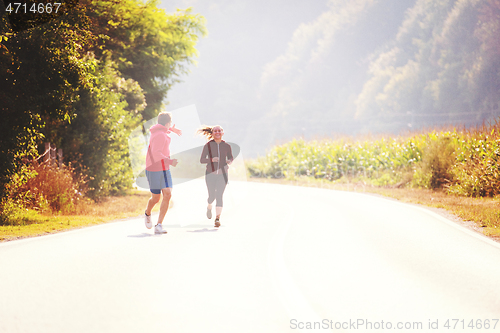 Image of young couple jogging along a country road