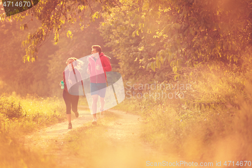 Image of young couple jogging along a country road