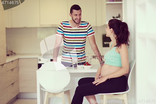 Image of couple eating fruit strawberries at kitchen