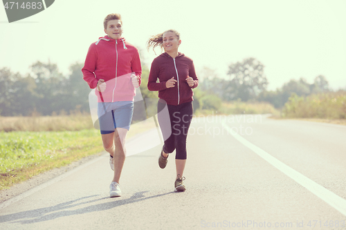 Image of young couple jogging along a country road