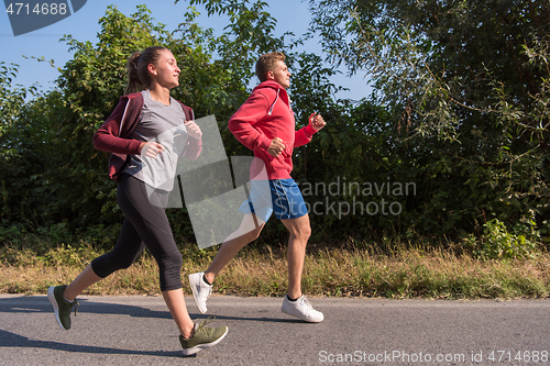 Image of young couple jogging along a country road