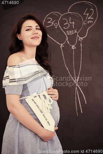 Image of Portrait of pregnant woman in front of black chalkboard