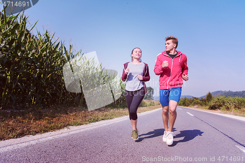 Image of young couple jogging along a country road