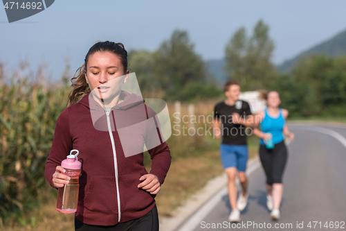 Image of young people jogging on country road