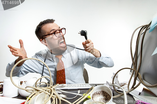 Image of Young man tangled in wires on the workplace