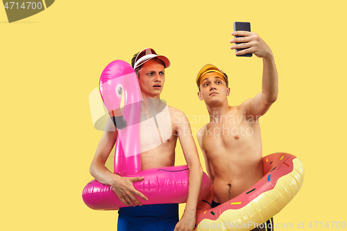 Image of Two young men isolated on yellow studio background