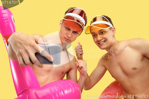 Image of Two young men isolated on yellow studio background