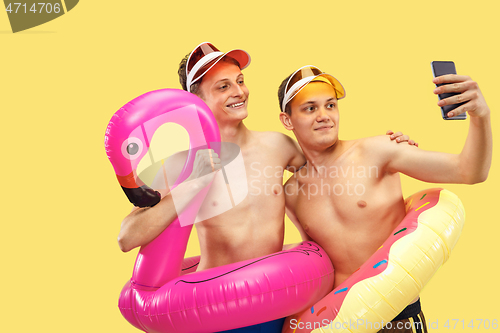 Image of Two young men isolated on yellow studio background