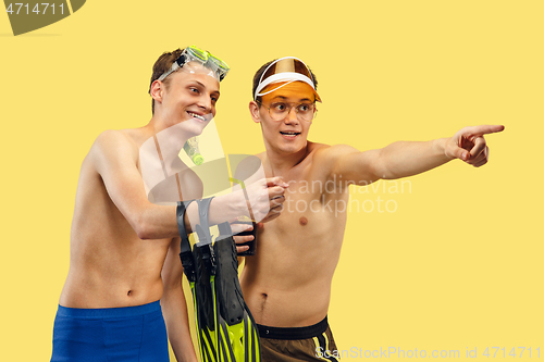 Image of Two young men isolated on yellow studio background
