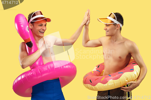 Image of Two young men isolated on yellow studio background